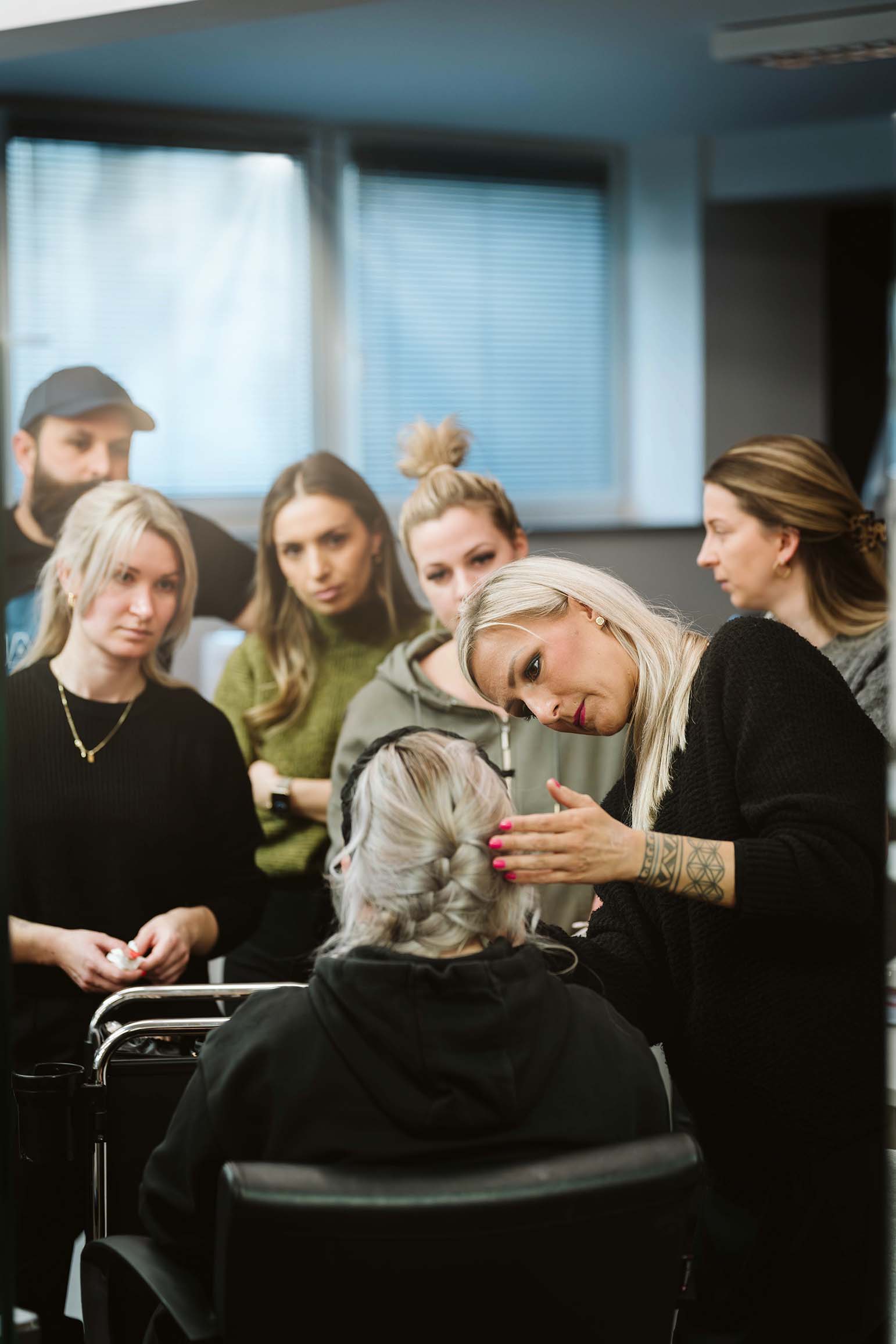Visagistig- und Make-up Dozentin beim Schminken eines Models vor Schülern