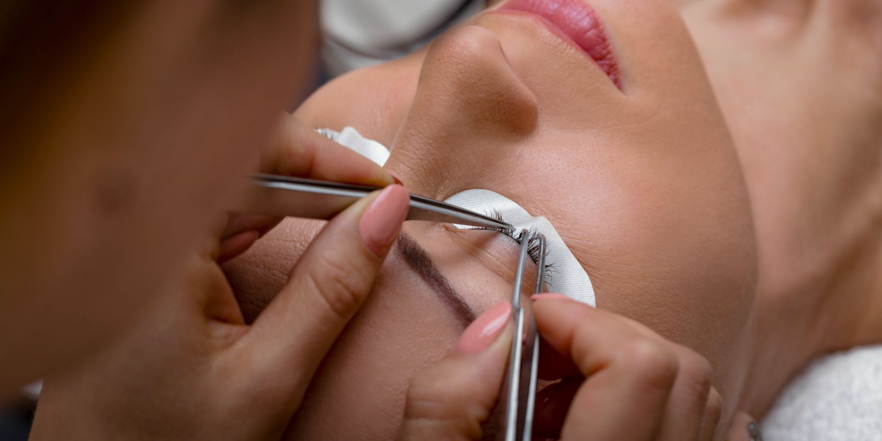Schönheitsbehandlung: Nahaufnahme der Pflege von Wimpern mit Pinzetten im Schönheitssalon