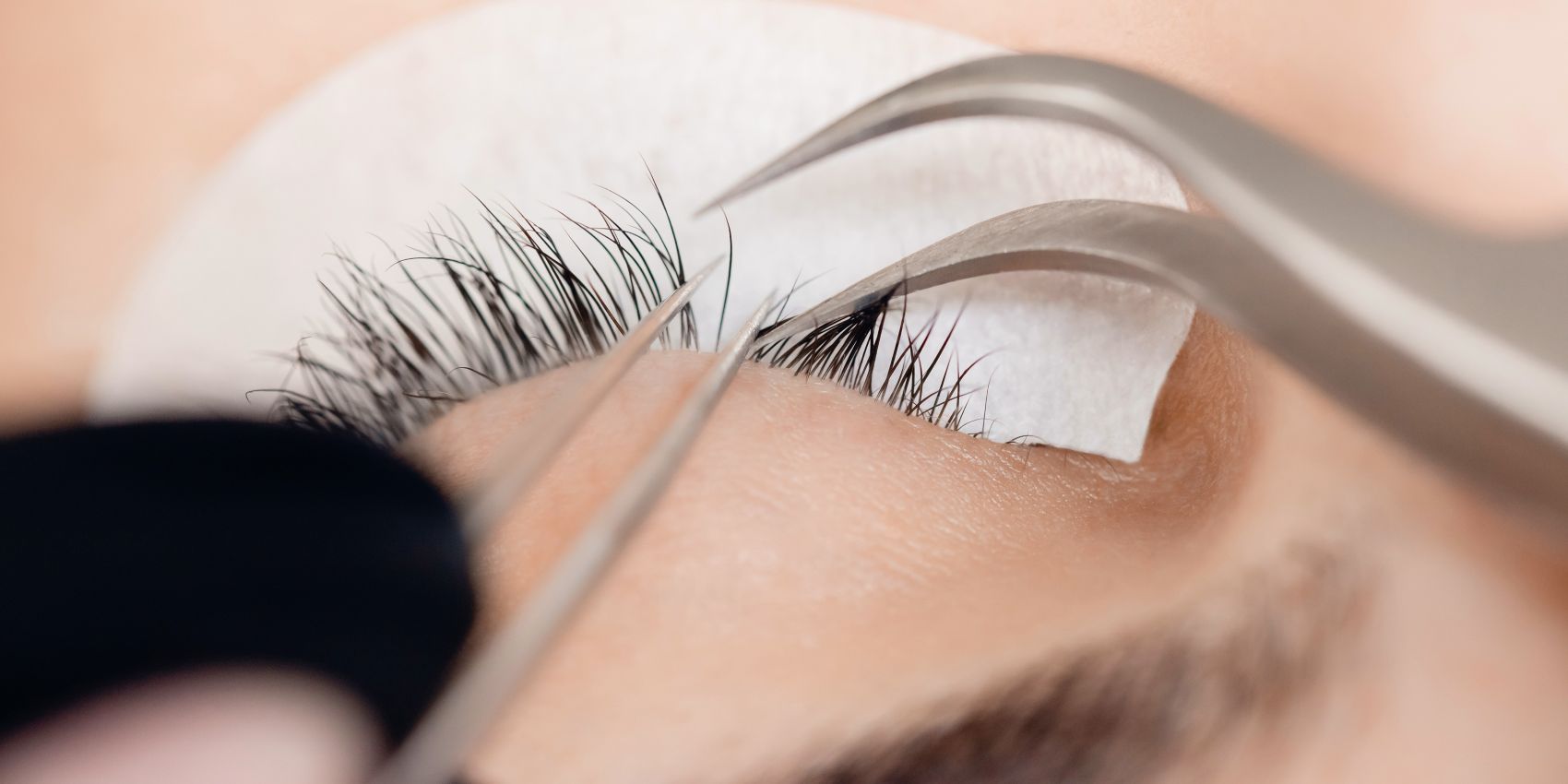 Schönheitsbehandlung: Nahaufnahme einer Wimperbehandlung mit Pinzette