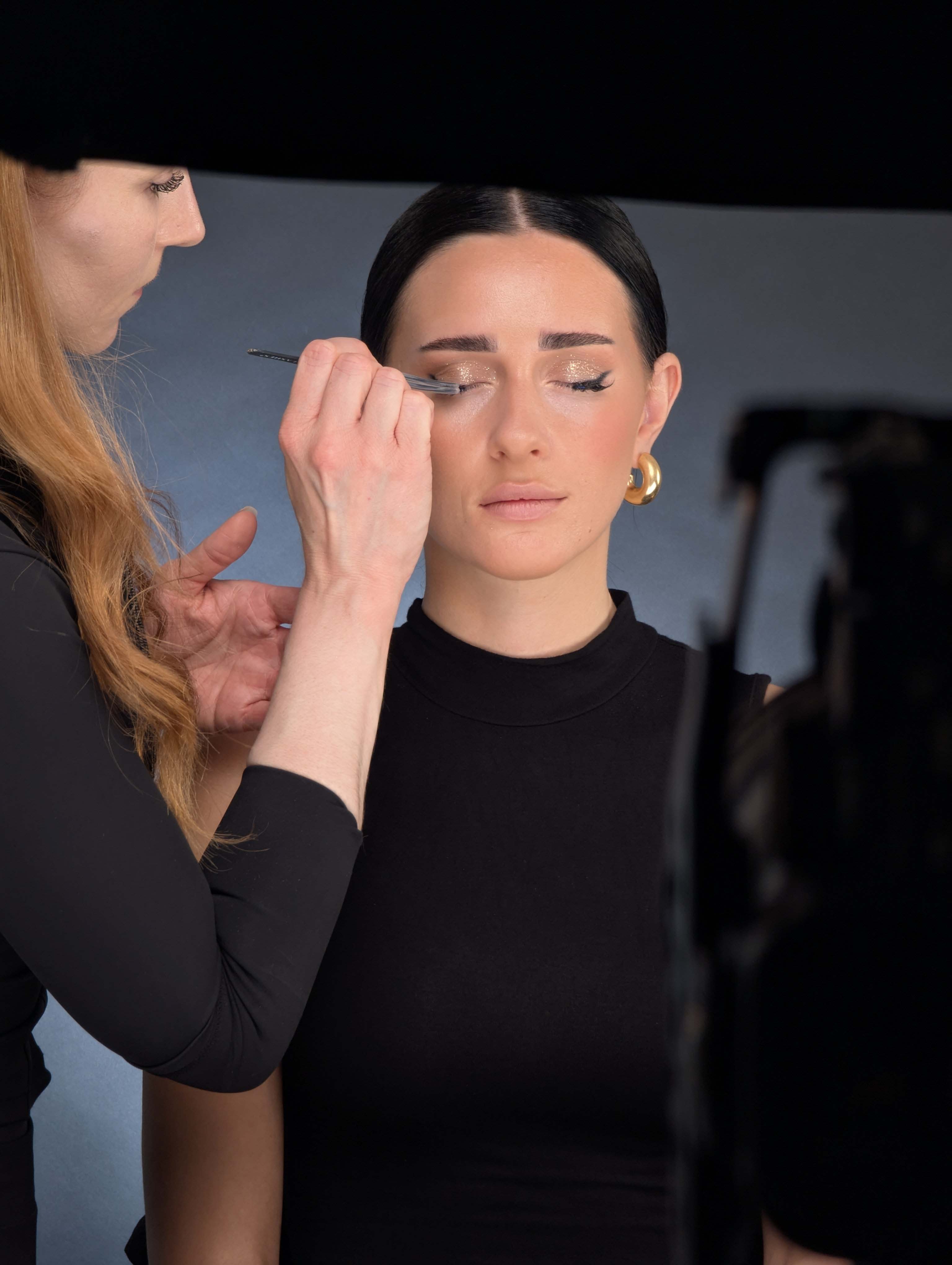 Backstage Foto einer Trainerin beim professionellem Schminken von Model. 
